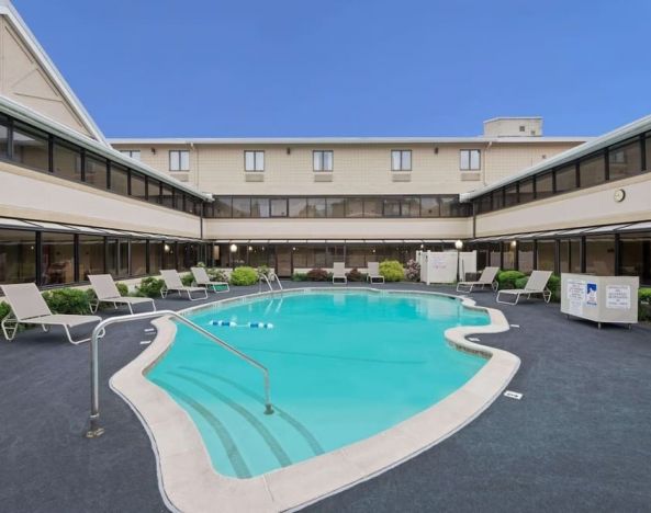 Stunning outdoor pool with pool chairs at Ramada By Wyndham Boston.