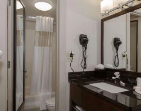 Guest bathroom with shower, bath, and hair dryer at Ramada By Wyndham Boston.