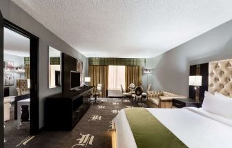 Spacious king bed with TV and lounge area at Wyndham Garden Dallas North.