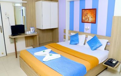 King bed in brightly lit room at Hotel Alka Residency.