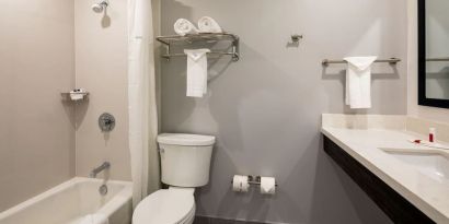 Private guest bathroom with combined shower and tub at Travelodge LAX By Wyndham.