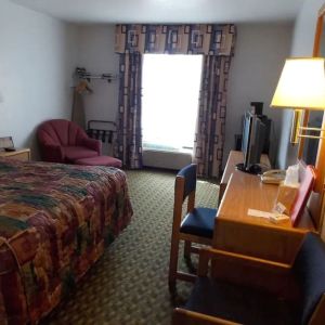 Day use room with natural light, work desk, TV screen and sofa at Norwood Inn Minneapolis Roseville. 