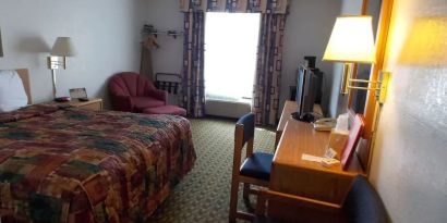 Day use room with natural light, work desk, TV screen and sofa at Norwood Inn Minneapolis Roseville. 