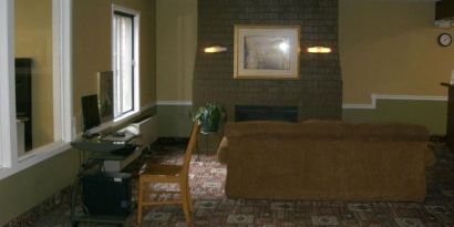 Lobby lounge and workspace with comfortable seating, fireplace and computer at Norwood Inn Minneapolis Roseville.