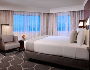 Royal Sonesta Houston Galleria king bed guest room, including windows, armchair, and coffee table.