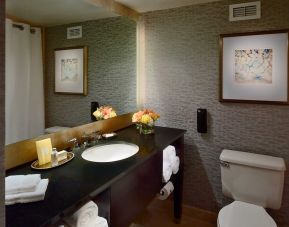 Guest bathroom in Royal Sonesta Houston Galleria, with lavatory, sink, and wide mirror.