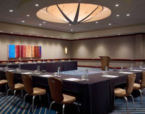 Hotel meeting room, with tables arranged in a U-shape facing a lectern, and seating for over a dozen attendees.