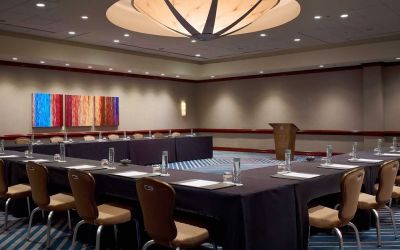 Hotel meeting room, with tables arranged in a U-shape facing a lectern, and seating for over a dozen attendees.