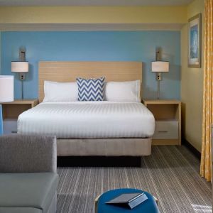 Sonesta ES Suites Tucson guest room, furnished with deluxe king bed, sofa, and television.