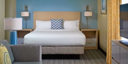 Sonesta ES Suites Tucson guest room, furnished with deluxe king bed, sofa, and television.