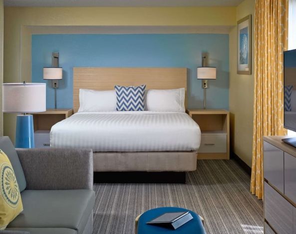 Sonesta ES Suites Tucson guest room, furnished with deluxe king bed, sofa, and television.