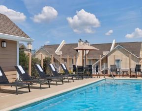 Sonesta ES Suites Tucson’s outdoor pool has a row of sun loungers, plus tables and chairs, by the side.