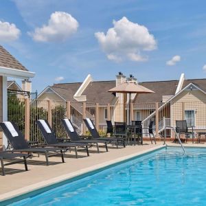 Sonesta ES Suites Tucson’s outdoor pool has a row of sun loungers, plus tables and chairs, by the side.