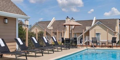 Sonesta ES Suites Tucson’s outdoor pool has a row of sun loungers, plus tables and chairs, by the side.