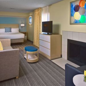Double bed guest room in Sonesta ES Suites Tucson, including lounge with sofa, armchair, and TV.