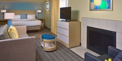 Double bed guest room in Sonesta ES Suites Tucson, including lounge with sofa, armchair, and TV.