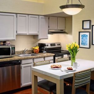 Sonesta ES Suites Tucson guest room kitchen area, equipped with hob, oven, microwave, sink, and fridge freezer, plus dining table.