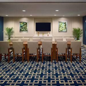 Meeting room in Sonesta ES Suites Tucson, featuring long wooden table, seating for twelve, and a large, wall-mounted television.