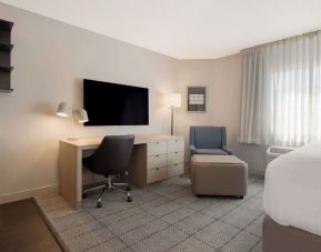 Guest room workspace in Sonesta Simply Suites Irvine East Foothill, furnished with desk, chair, lamp, and television.