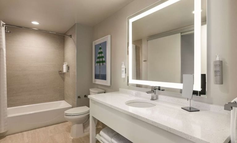 Private guest bathroom with tub and free toiletries at Embassy Suites By Hilton Panama City Beach Resort.