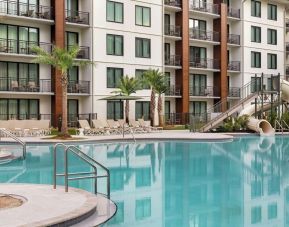 Outdoor pool with water slide and lounge chairs at Embassy Suites By Hilton Panama City Beach Resort.
