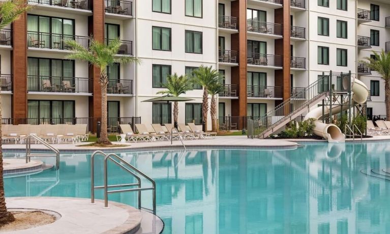 Outdoor pool with water slide and lounge chairs at Embassy Suites By Hilton Panama City Beach Resort.