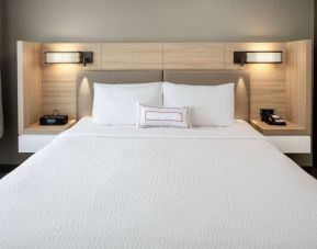Sonesta Select Nashville Airport Suites deluxe king bed room, featuring bedside lamps and telephone.