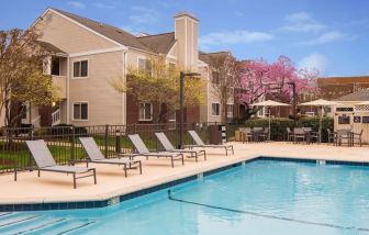 Shaded tables and chairs, as well as sun loungers, are by the side of Sonesta ES Suites Nashville Brentwood’s outdoor pool.