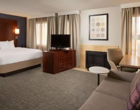 Sonesta ES Suites Nashville Brentwood king bed guest room, furnished with sofa, desk, and TV.