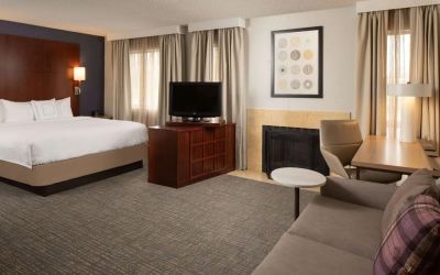 Sonesta ES Suites Nashville Brentwood king bed guest room, furnished with sofa, desk, and TV.