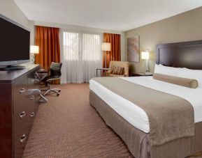 Sonesta Miami Airport double bed guest room, furnished with television, armchair, and workspace desk and chair.