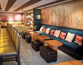 The hotel bar has a mix of traditional tall stools and table seating, and a hard floor.