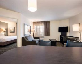 Sonesta Simply Suites Denver West Federal Center guest room lounge, furnished with sofa, chairs, coffee table, and TV.