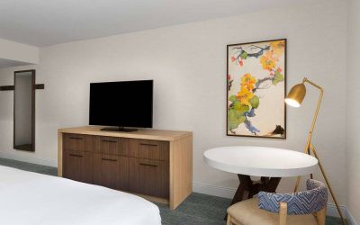 Double bed guest room in Sonesta Silicon Valley, furnished with widescreen television, and workspace desk, chair, and lamp.
