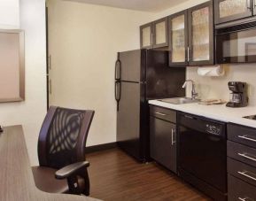 Sonesta Simply Suites Cleveland North Olmsted Airport guest room workspace desk and chair, and adjacent kitchenette.