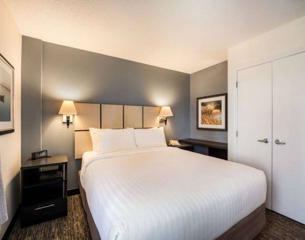 Guest room in Sonesta Simply Suites Albuquerque, furnished with double bed, art on the wall, and bedside telephone.