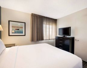 Sonesta Simply Suites Baltimore BWI Airport double bed guest room, featuring window, bedside lamp, and television.