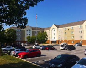 The hotel exterior features ample parking, pleasant greenery, and a fluttering Stars and Stripes flag.