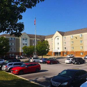 The hotel exterior features ample parking, pleasant greenery, and a fluttering Stars and Stripes flag.