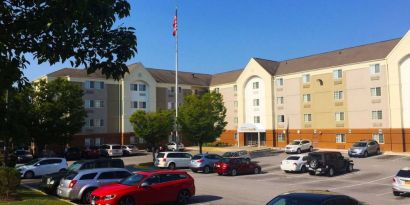 The hotel exterior features ample parking, pleasant greenery, and a fluttering Stars and Stripes flag.