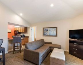 Sonesta ES Suites Dulles Airport guest room lounge, furnished with sofa, chairs, desk, and TV.