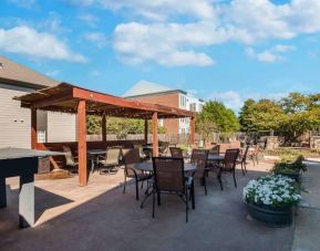 Sonesta ES Suites Dulles Airport’s terrace features tables and chairs, some under cover, and potted plants.