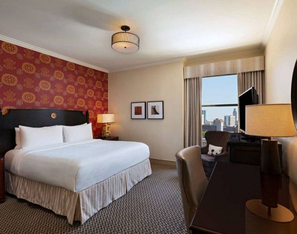 The Stephen F Austin Royal Sonesta Hotel double bed guest room, including window and workspace desk and chair.