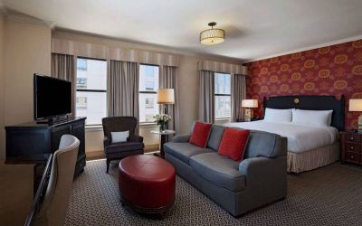 Double bed guest room in The Stephen F Austin Royal Sonesta Hotel, furnished with sofa, chair, desk, and television.