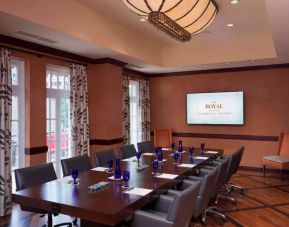 The Stephen F Austin Royal Sonesta Hotel meeting room, with long wooden table, ten swivel chairs, and wall-mounted television.