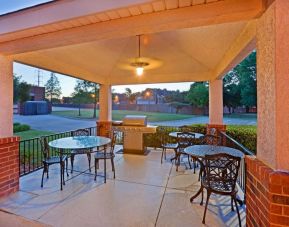 The hotel’s gazebo provides outdoor tables and chairs under cover, with greenery nearby and a barbecue.