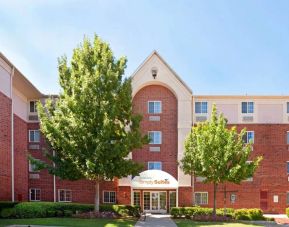 Sonesta Simply Suites Arlington’s exterior has clear signage, beautiful lawns, and towering trees.
