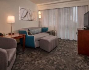 Sonesta Select Arlington Rosslyn guest room lounge with sofa, armchair, window, and TV.