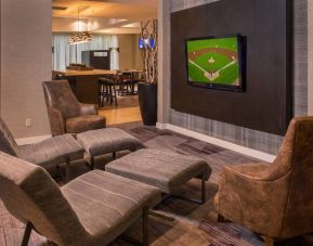 Sonesta Select Arlington Rosslyn’s lobby features a large, wall-mounted TV, with armchairs and reclined seating with footstools.