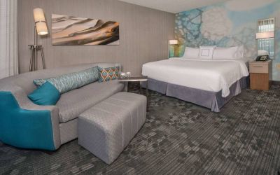 Sonesta Select Allentown Bethlehem Airport double bed guest room, with art on the wall, sofa, and long footstool.